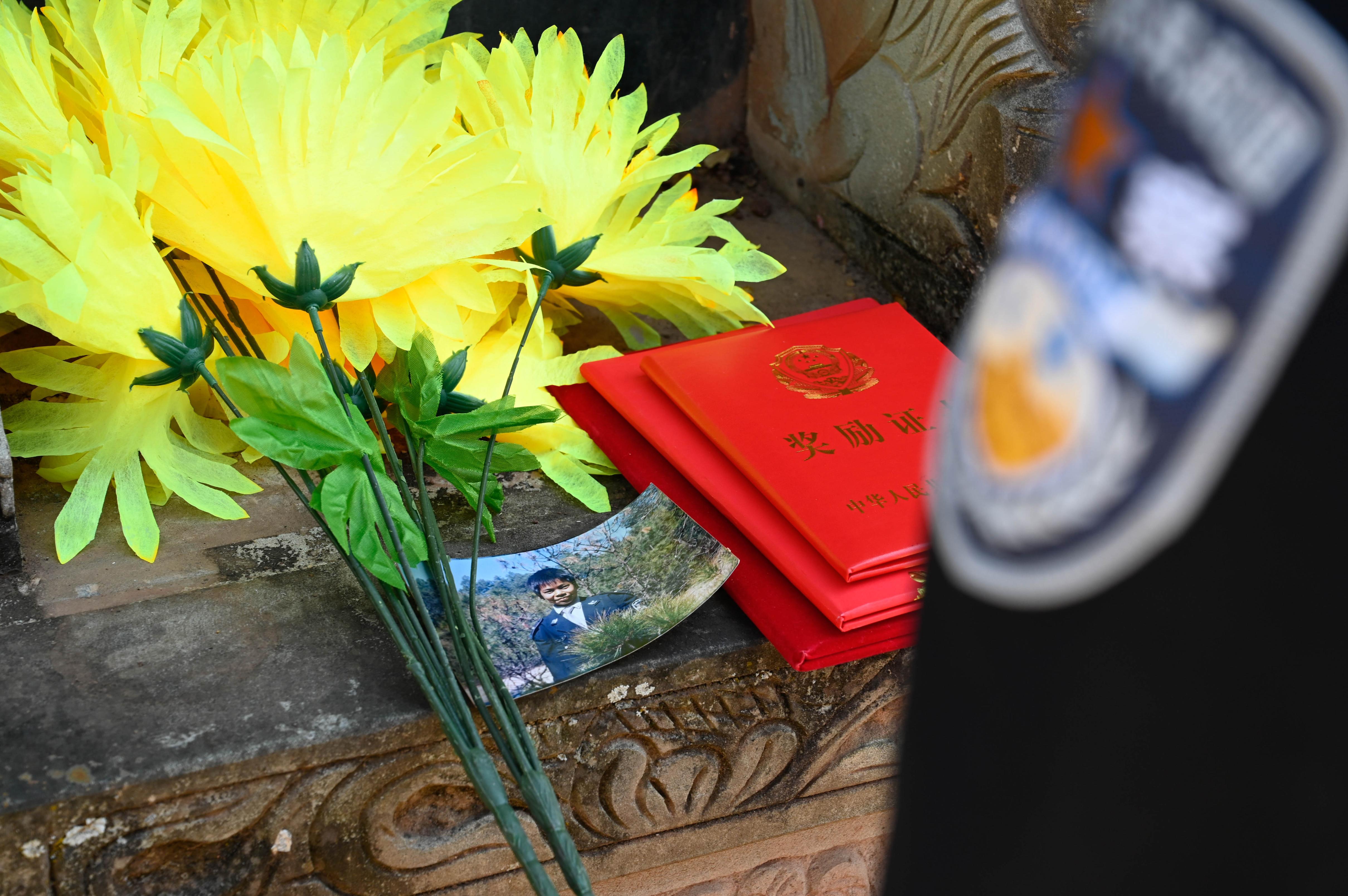 曾经偷穿爸爸警服的小女孩把荣誉证书带到了父亲墓前